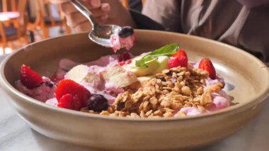 Taze meyve ve tahıl gevreğiyle tatlandırılmış yoğurdun tadını çıkarıyorum..