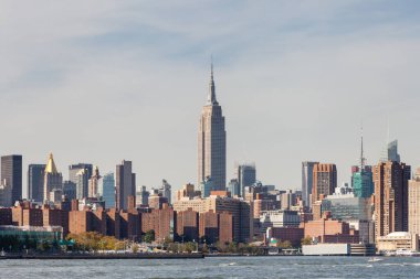 Midtown Manhattan, Amerika Birleşik Devletleri 'ndeki East River, New York City' den izleniyor. Empire State Binası çevredeki binaların üzerinde duruyor..