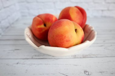 Olgun kırmızı-sarı şeftaliler beyaz bir tabakta yatıyor. Sağlıklı beslenme. Meyve diyeti. makro çekim