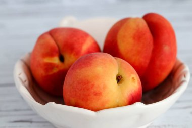 Olgun kırmızı-sarı şeftaliler beyaz bir tabakta yatıyor. Sağlıklı beslenme. Meyve diyeti. makro çekim