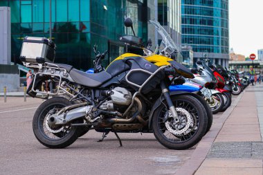 Nakliye motosikletleri yüksek katlı bir binanın yanında sıra sıra bekliyor. Yarış motosikletleri.