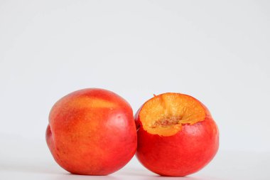 Dekoratif siyah beyaz fare beyaz arka planda tatlı ve lezzetli şeftaliyi kokluyor ve yiyor..