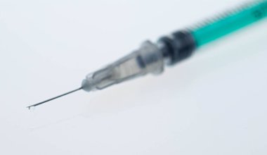 Tıbbi insülin şırıngasının iğnesinden küçük bir damla ilaç damlıyor. İnanılmaz makro..