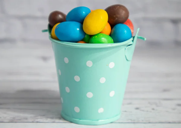 Barevné bonbóny leží v malém dekorativním kbelíku s mátovou barvou. Detailní záběry miniatur na bílém cihlovém pozadí. Makro — Stock fotografie