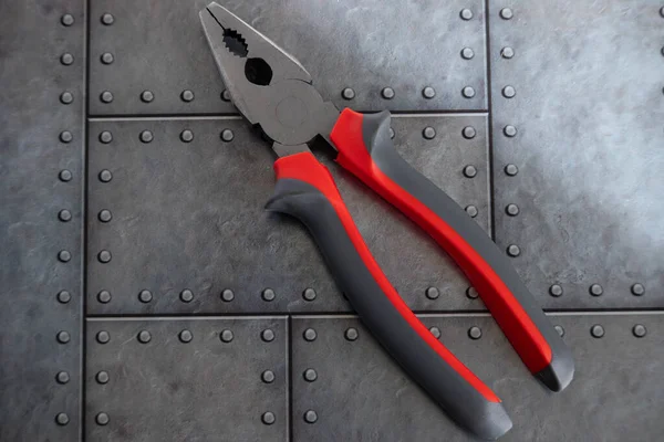 Kırmızı saplı kerpeten, gri demir arka planda yatıyor.