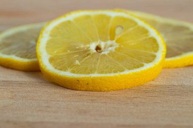 Tahta bir arka planda parlak sarı sulu limon dilimi. Meyve çekirdeğinin makro görüntüsü.