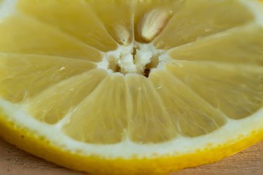 Tahta bir arka planda parlak sarı sulu limon dilimi. Meyve çekirdeğinin makro görüntüsü.