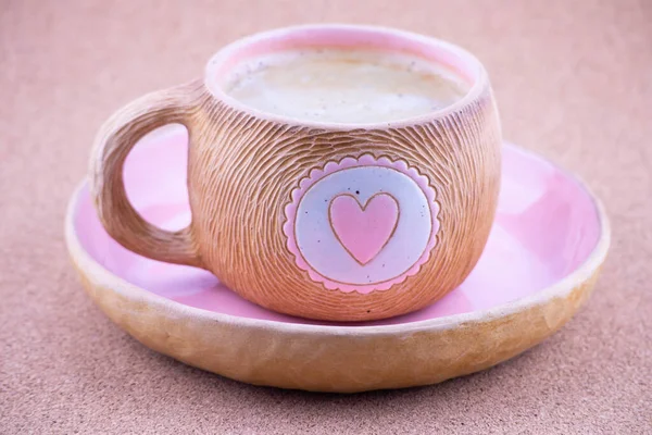 Pembe kalpli kahverengi seramik bardak. Bir fincan kahve ya da çay doldurulur. Tabağın üzerinde böğürtlen ve fıstıklı acı siyah çikolata var. Yakın plan..