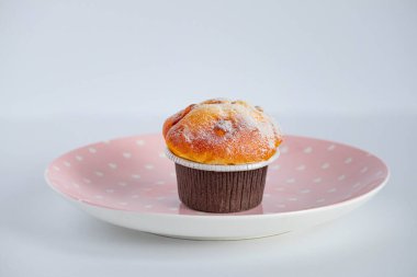 Kahverengi kağıt kaplar içinde, pembe bir tabağa konmuş vanilyalı kek. yan görünüm.