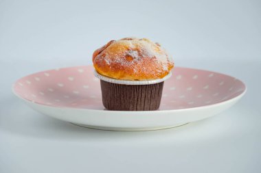 Kahverengi kağıt kaplar içinde, pembe bir tabağa konmuş vanilyalı kek. yan görünüm.