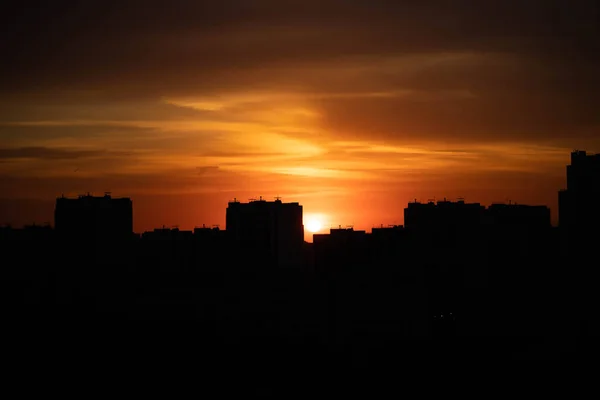 Big city in the rays of the sunset. High-rise black houses and red fiery sky