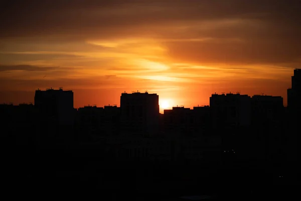 Big city in the rays of the sunset. High-rise black houses and red fiery sky