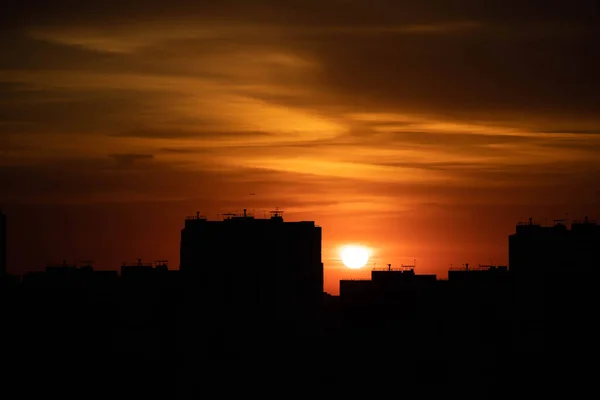 Big city in the rays of the sunset. High-rise black houses and red fiery sky