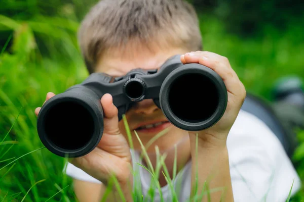 curious boy looks for wildlife through binoculars in the park. Exploring the world, bird watching. Outdoor activities. boy looking far into the distance, searching for direction. imagination, freedom.