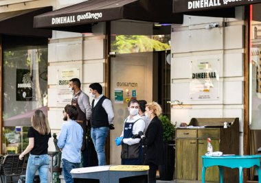 Mavi masadaki ıslak mendilli dezenfektan ve sokağın girişinde duran 