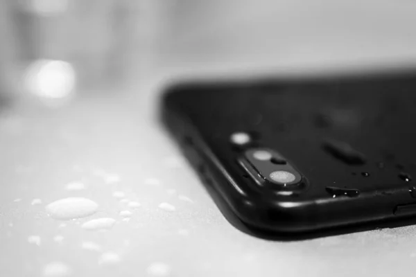 Close up of  black smartphone camera lens with water inside and drop lits on the backside. Internal part sof water damage concept. Blank sapce image.