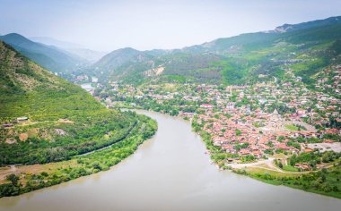 Mtkvari nehri hava perspektifinden. Mtskheta kasabasının arkaplan manzarası ve yeşil yaz dağlarının manzarası.