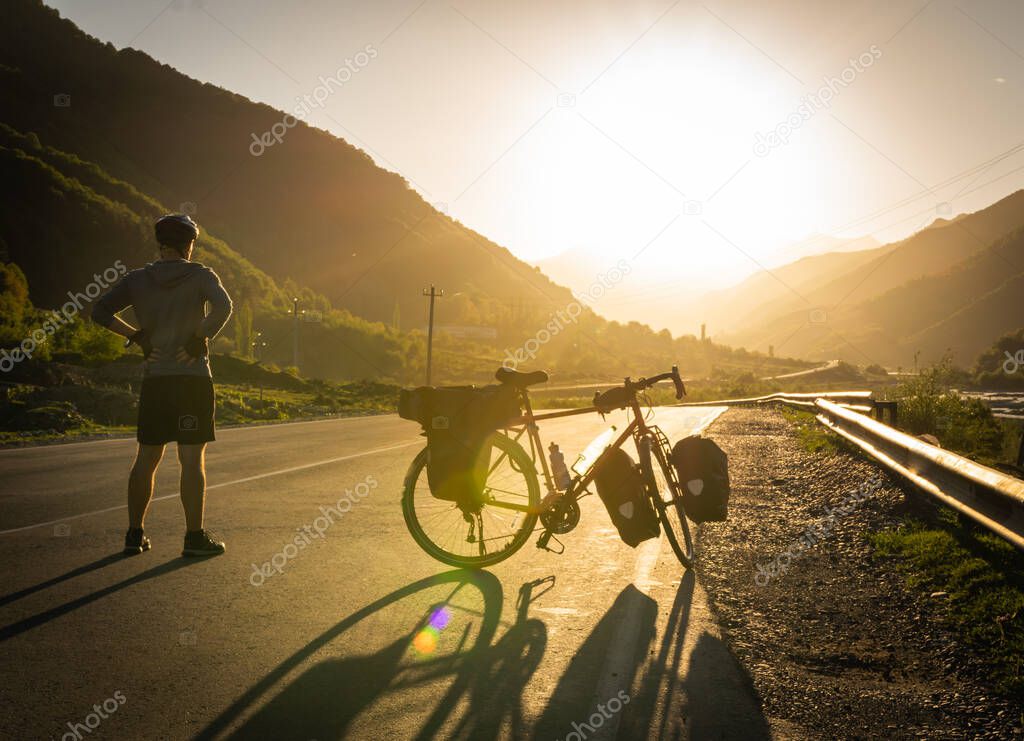 Cyclist enjoy panoramic view of the mountains on the road while break time. Healthy lifestyle and bicycle touring. Ecological travel.