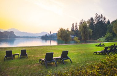 Slovenya 'da sabah saatlerinde Orta Avrupa ve Slovenya' da Nature retriet 'te kanayan gölün kenarında hiç insan bulunmayan çimlerin üzerinde çok sayıda koltuk bulunuyor..