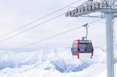 Boş beyaz / kırmızı kapalı kayak asansörü kabini ve arka planda beyaz dramatik dağlar. Sezon sonu konsepti. Gudauri. Georgia.2020