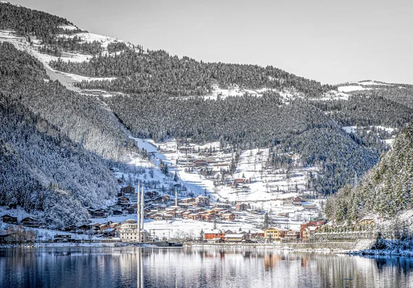 Uzungol scenic lake  panorama in inter with traditional turkish mosque and living houses and forest in the background.Winter travel holidays in Turkey. 2020