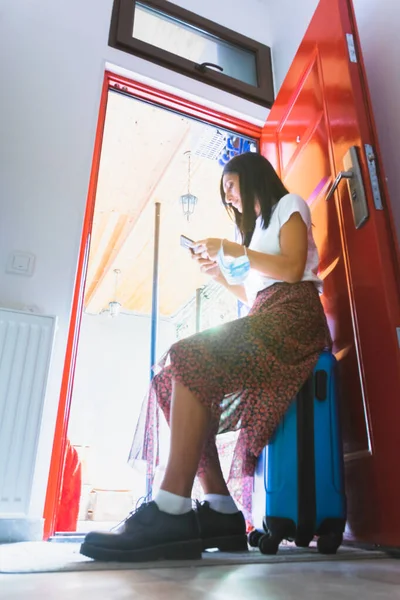 Молода Довгошерста Біла Жінка Сидить Синій Валізі Дверях Дивиться Телефон — стокове фото