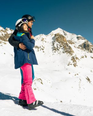 Kafkasyalı genç çift, kışın karlı dağlara bakarken sarılıp eğleniyorlar. Tatillerde kayak yaparak uzaklaşmak. Tetnuldi kayak merkezinin bakış açısı. Kafkas dağları yüksek irtifa azaltılıyor