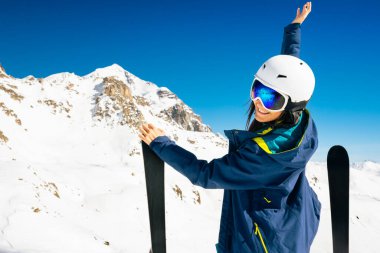 Genç mutlu beyaz kadın kayaklarla poz veriyor. Alp bölgesindeki kameralara bakıyor. Tatillerde kayak yaparak uzaklaşmak. Kafkasya dağları el değmemiş yüksek irtifa taşıma kavramının tepesinde.