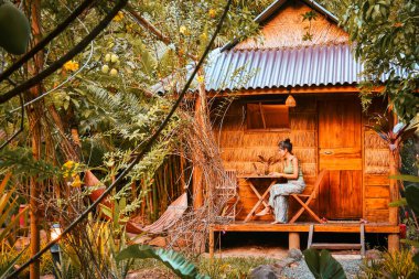 Kafkasyalı genç hippi kadın oturur bilgisayar serbest çalışır, seyahat blogu yazar ya da internet araştırması yapar, güneydoğu Asya tropikal adalarında seyahat ederken internetten çalışır.