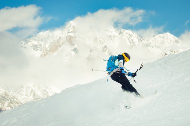 Cool Kayakçı arka planda dağlarla karlı yamaçta ters kayak numarası yapıyor.