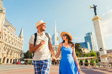 Batumi, Gürcistan - 19 Ağustos 2025: Batumi şehir sokağında tatil yaparken eğlenen iki turist - tatilde birlikte gülen mutlu arkadaşlar - insanlar ve tatil kavramı. Medea heykeli