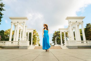 Mavi elbiseli kadın Batumi sütunlarına doğru yürüyor, Batumi Bulvarı, Gürcistan 'da beyaz sütunlu neoklasik şehir simgesi, Karadeniz turizmi, tarih ve kültür mimarisinin sembolü.