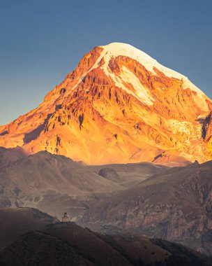 Gürcistan 'da Stepantsminda yakınlarında Gergeti Trinity Kilisesi' nin önünde kar tepesinde dramatik bir gün doğumu yaşandı.