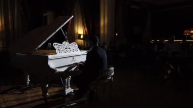 Bir piyanistin seyirci arka planında kendi müziğini icra edişi. Gece kulübünde klasik ve caz müzik konseri
