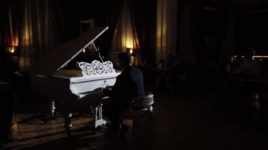 Bir piyanistin seyirci arka planında kendi müziğini icra edişi. Gece kulübünde klasik ve caz müzik konseri