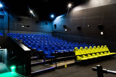 Mavi ve sarı koltuklu sinema salonu. Boş bir oditoryuma geniş açı ve resimli ışıklar.