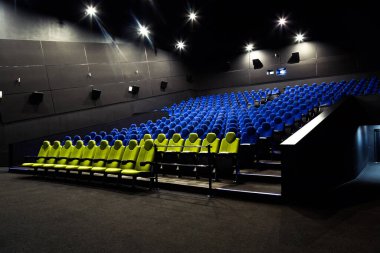 Mavi ve sarı koltuklu sinema salonu. Boş bir oditoryuma geniş açı ve resimli ışıklar.