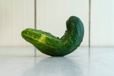 Açık mutfakta, masada yatan deforme olmuş ev yapımı salatalık. Çiftçi sebzeleri beslenme için iyidir çünkü birçok vitamin ve mikro element içerir. Kopyalama alanı olan yatay fotoğraf.