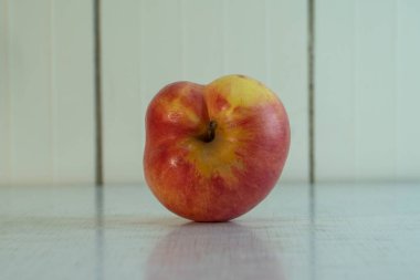 Açık kırsal masada sarı benekli, biçimsiz kırmızı elma uzanıyor. Köy meyvesi yemek için iyidir çünkü birçok vitamin ve mikro element içerir. Peyzaj yönelimli fotoğraf, kopyalama alanı.