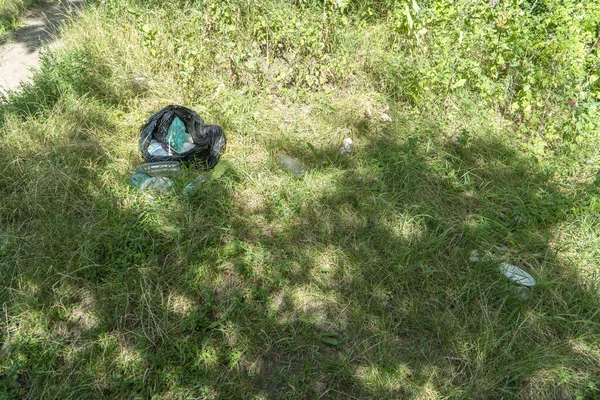 Czarna Plastikowa Torba Śmieciami Butelkami Kubki Talerze Leżą Leśnej Polanie — Zdjęcie stockowe