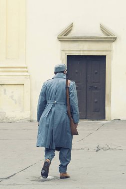 Avusturya-Macaristan ordusuna asker onun omuz kapalı bir Roma Katolik Kilisesi s kapının yürüyüş bir tüfekle. Kış gri sarı cephe karşı tek tip.