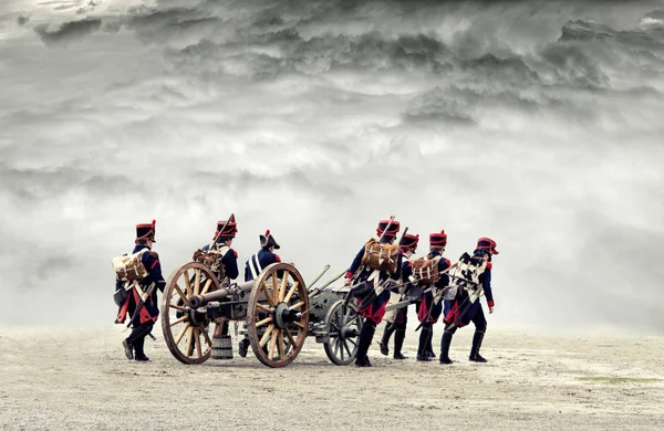 Soldados napoleónicos marchando en tierra abierta con nubes dramáticas, tirando de un cañón . —  Fotos de Stock