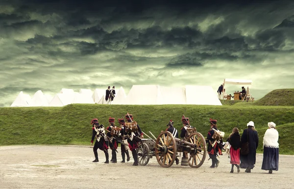 Napoleontische militairen en vrouwen marcheren en het trekken van een kanon langs een Franse camping met stormachtige wolken hierboven. Soldaten weer terug naar thuisbasis. Geen identificeerbare mensen — Stockfoto