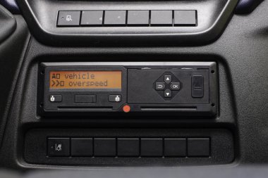 Digital tachograph display reads Vehicle Overspeed. No personal data. Tachograph in a van clipart