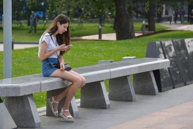 Moskova, Rusya, 18 Mayıs 2018. Parkta bir akıllı telefon ile genç kız