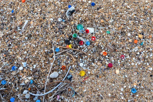 Plastic bottle caps scattered on the beach, environmental pollution