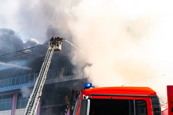 Bombeiros nas escadas extinguem um grande incêndio — Fotografia de Stock