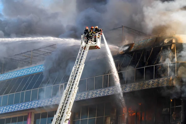 Bombeiros nas escadas extinguem um grande incêndio — Fotografia de Stock