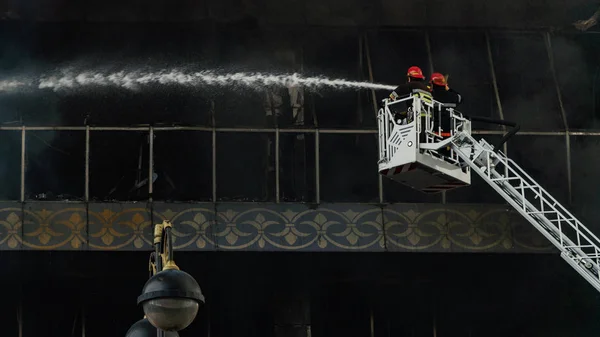 Bomberos en las escaleras apagan un gran incendio —  Fotos de Stock