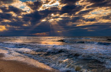 Altın kum, küçük dalgalar ve güzel bir dramatik gökyüzü ile bir plaj